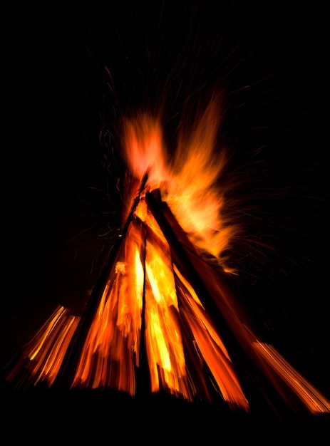 Großes Lagerfeuer gegen dunklen Nachthimmel. Feuerflammen auf schwarzem Hintergrund