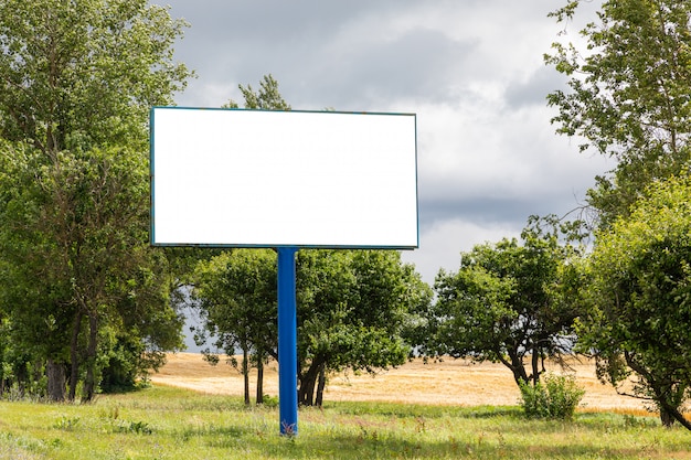 Großes leeres Plakatmodell entlang der Autobahn gegen Wiese mit Bäumen