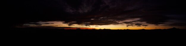 Großes natürliches Panorama der Salzwiesen Salar de Uyuni in Bolivien bei Sonnenuntergang. Erstaunliche farbenfrohe Aussicht auf die untergehende Sonne am späten Abend bei gutem Wetter. Konzept der Reise. Copyright-Bereich für die Website