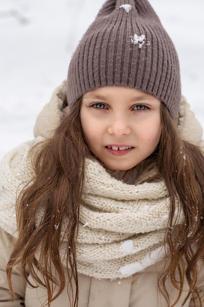 großes Porträt eines süßen blonden Mädchens in einem warmen Hut im Winter