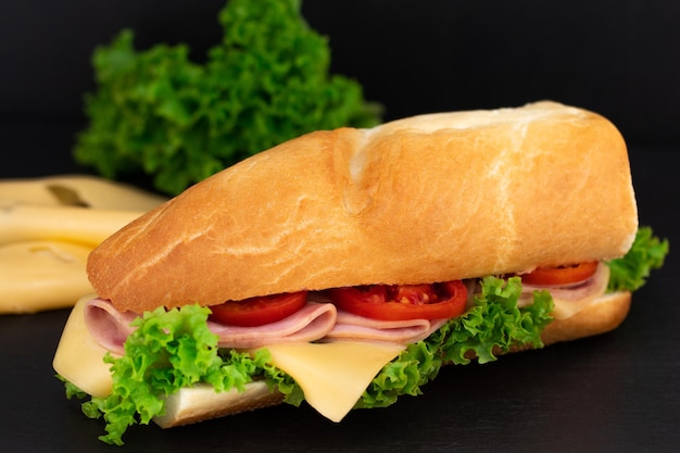 Großes Sandwich mit Fleisch und Käse auf dunklem Hintergrund.