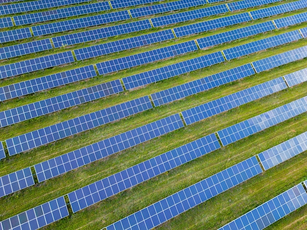 Großes Solarkraftwerk auf einer grünen Wiese aus der Luft