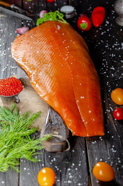 Großes Stück Rotbarschfilet mit Gemüse und Gewürzen und frischen Kräutern Holzschneidebrett