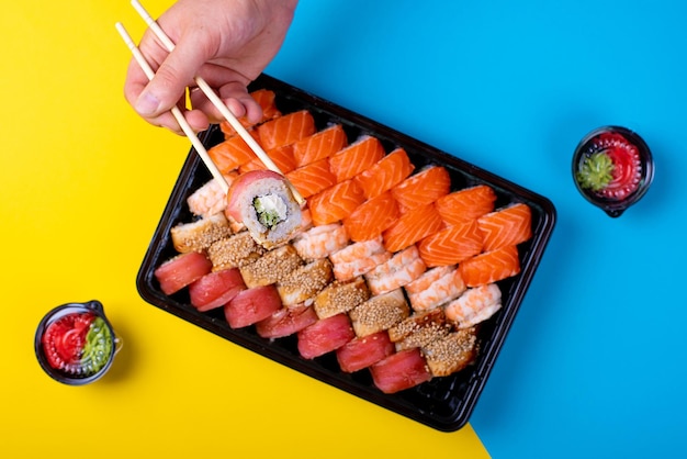 Großes Sushi-Set mit Stäbchen auf blauem und gelbem Hintergrund Japanische Küche