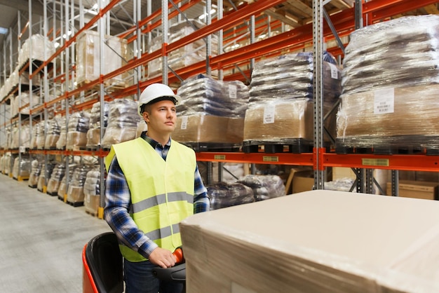 großhandel, logistik, verladung, versand und personenkonzept - mann oder lader auf gabelstapler, der fracht im lager lädt