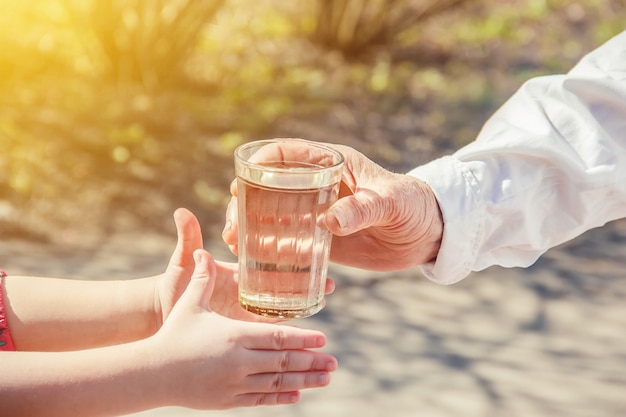 Großmutter, die einem Kind ein Glas sauberes Wasser gibt. Selektiver Fokus