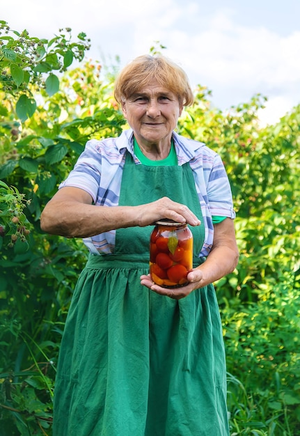 Großmutter, die Tomaten für den Winter einmacht. Selektiver Fokus.