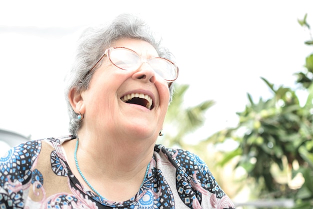 Großmutter mit Brille und grauem Haar lächelt sehr glücklich mit Zahnersatz