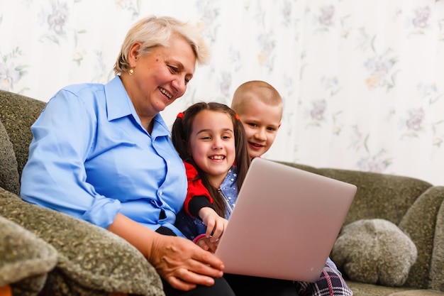 Großmutter mit Enkelkindern mit Laptop zu Hause