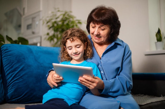 Großmutter mit ihrer Enkelin schaut begeistert auf den Tablet-Bildschirm