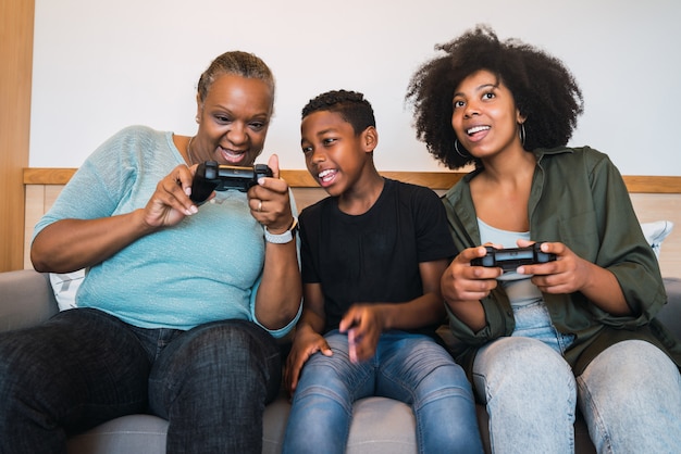 Großmutter, Mutter und Sohn spielen zu Hause Videospiele.
