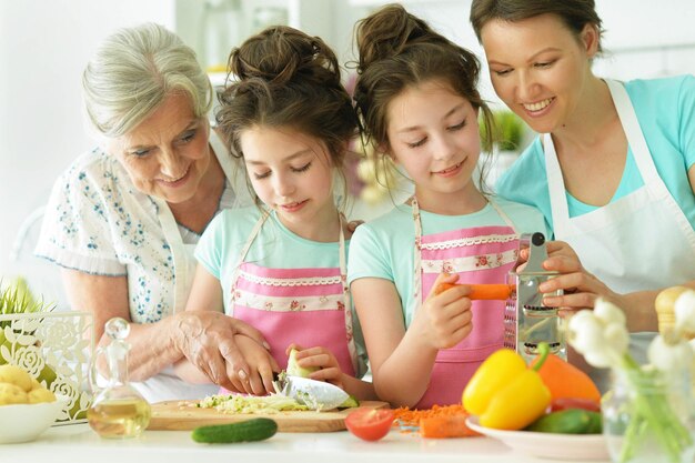 Großmutter, Mutter und zwei Töchter kochen Frühstück