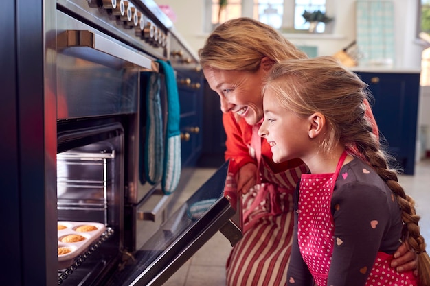 Großmutter und Enkelin nehmen frisch gebackene Cupcakes aus dem Ofen in der Küche zu Hause
