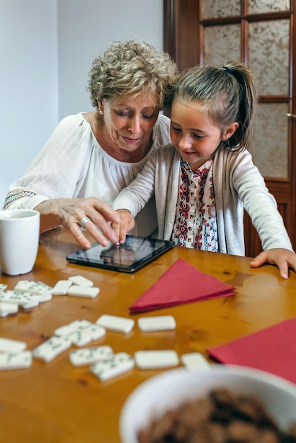 Großmutter und Enkelin spielen mit dem Tablet im Wohnzimmer