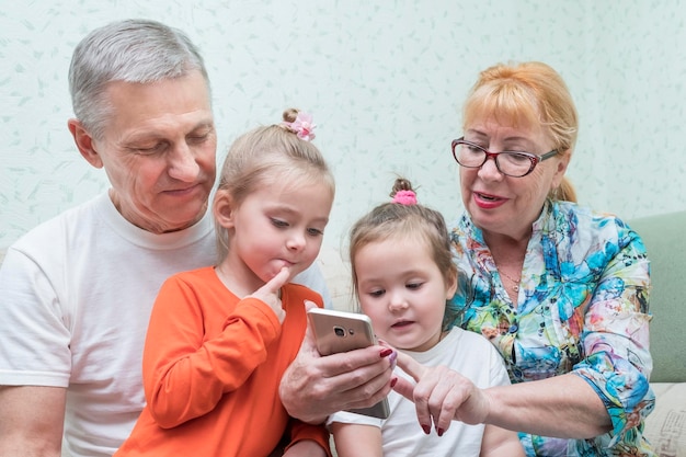 Großmutter und großvater zeigen ihren enkelinnen ein smartphone