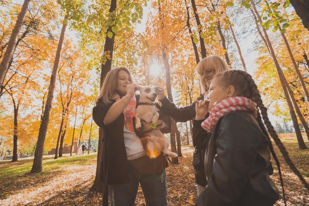 Großmutter und Mutter mit Enkelin, die Spaß mit Hund in der Herbstsaison-Generationsfreizeit haben