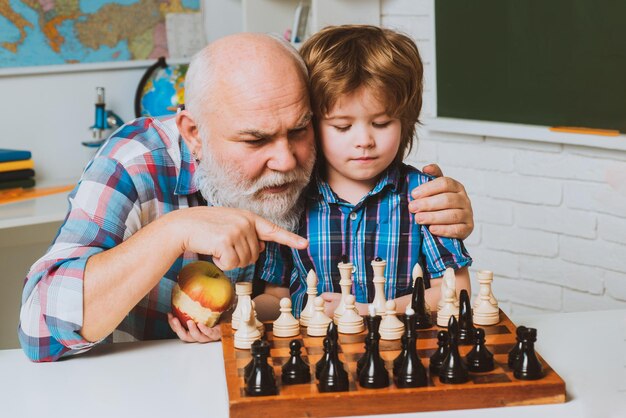 Großvater der Männerfamilie, der Enkel beibringt, Schach Eltern und Elternschaft zu spielen