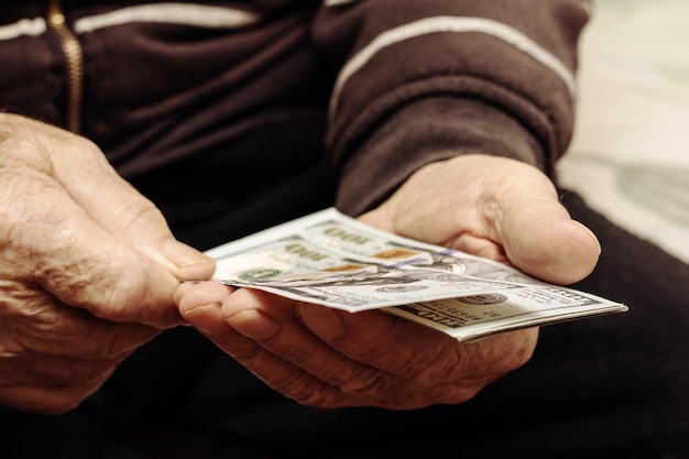 Großvater hält Geld in seinen Händen Ein älterer Mann zählt Dollar