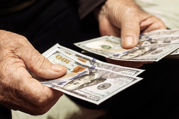 Großvater hält Geld in seinen Händen Ein älterer Mann zählt Dollar