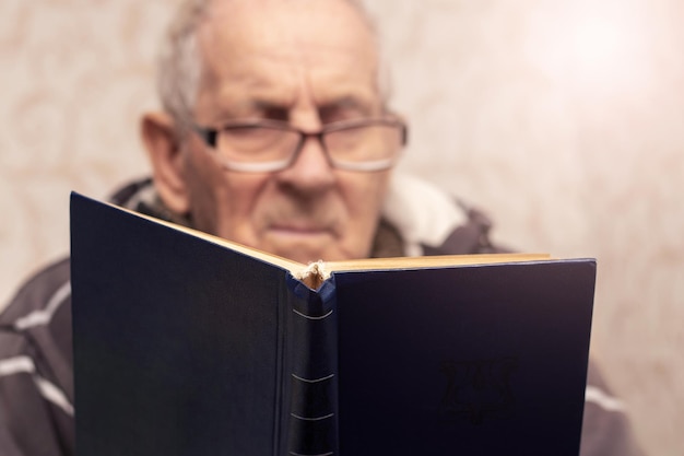 Großvater mit Brille liest ein Buch im Raum Freizeit für ältere Menschen