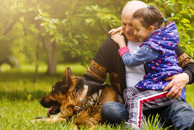 Großvater mit Enkelin und einem Hund im Garten