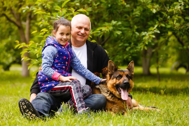 Großvater mit Enkelin und einem Hund im Garten