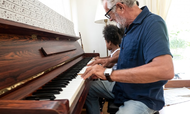 Großvater spielt Klavier mit kleinem Mädchen