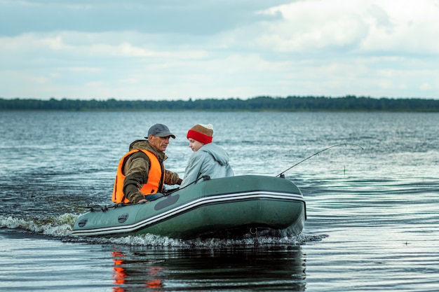 Großvater und Enkel fahren ein Motorboot auf dem See.