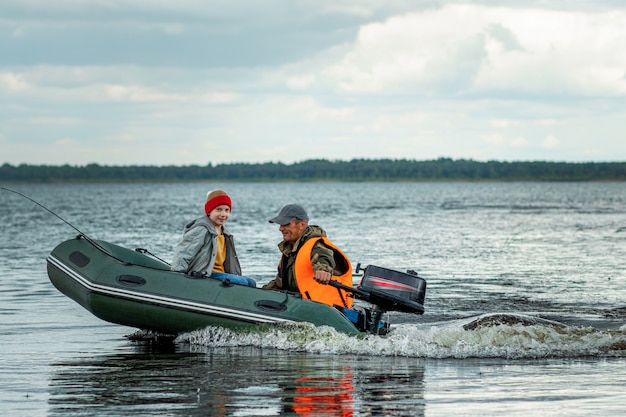 Großvater und Enkel fahren ein Motorboot auf dem See.