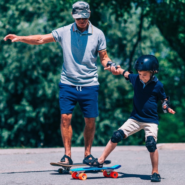 Großvater und Enkel fahren zusammen Skateboard