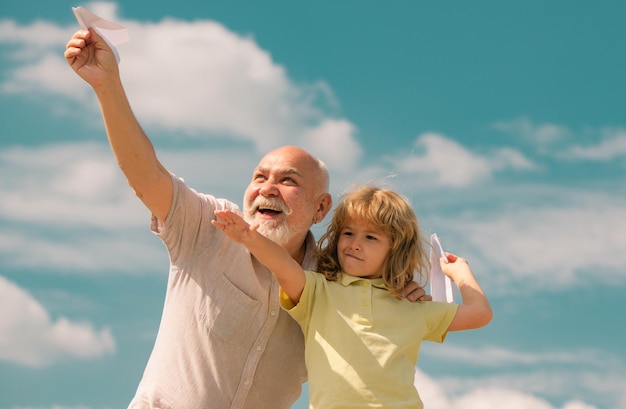 Großvater und Enkel mit Papierflugzeug über blauen Himmel und Wolken Männer Generation Großvater und