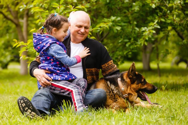 Großvater und Enkelin gehen mit Hund spazieren