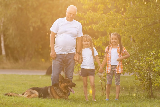 Großvater und Enkelinnen, die mit dem Hund spazieren gehen