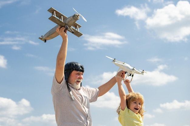 Großvater und Sohn mit Flugzeug und Quadrocopter-Drohne über blauem Himmel und Wolkenhintergrund Männer generati