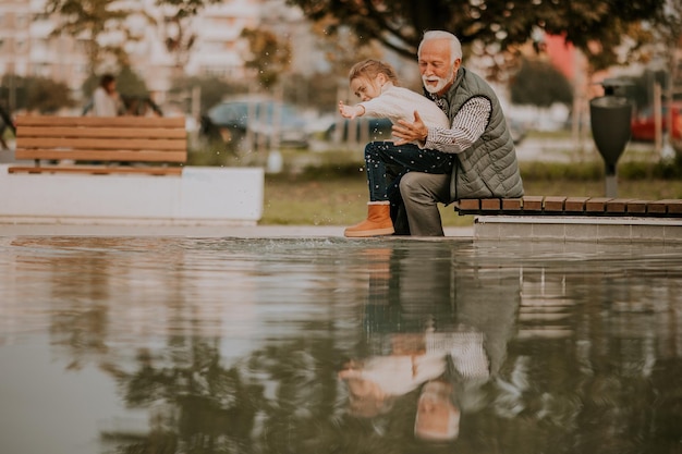 Großvater verbringt am Herbsttag Zeit mit seiner Enkelin am kleinen Wasserbecken im Park