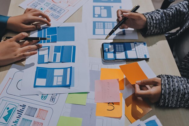 Group of young application developers analyzing uxui mobile app templates during a working meeting