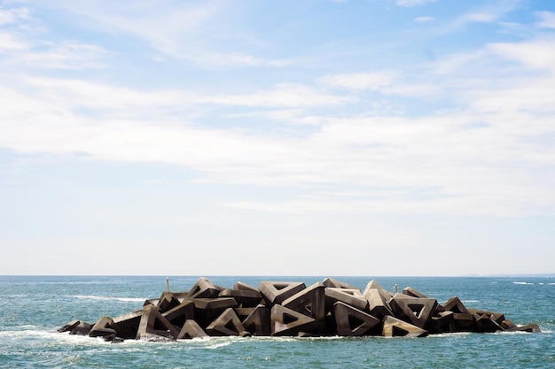 Groynes en medio del mar contra el cielo nublado