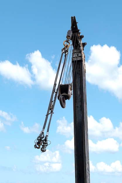 Grua amarela com ganchos e fundo de céu azul