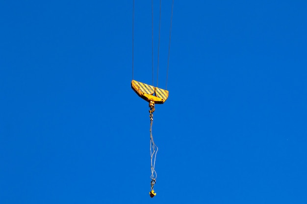 Foto grúa de construcción y gancho de grúa. concepto de operación y elevación de carga, fondo de cielo azul