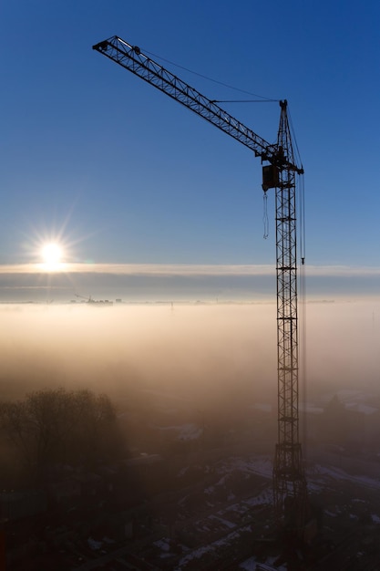 Grúa de construcción en la niebla de la mañana Amanecer niebla de la mañana sitio de construcción grúa torre Mística mañana de niebla en la ciudad al amanecer Paisaje urbano