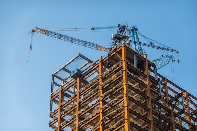 Grúa de construcción en la parte superior del rascacielos de la ciudad contra el cielo azul