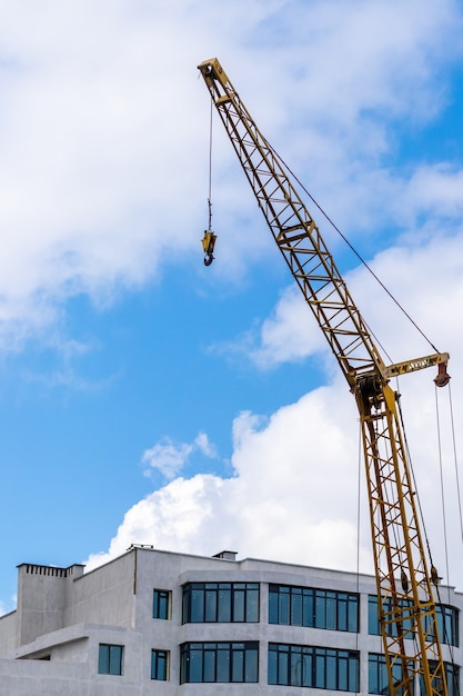 Grúa de construcción sobre un fondo del cielo cerca del nuevo edificio