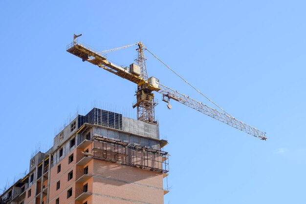 Foto grúa para la construcción de torres contra el cielo azul y el sol construcción de una nueva casa construción de nuevos edificios con una grúa grúa para torres