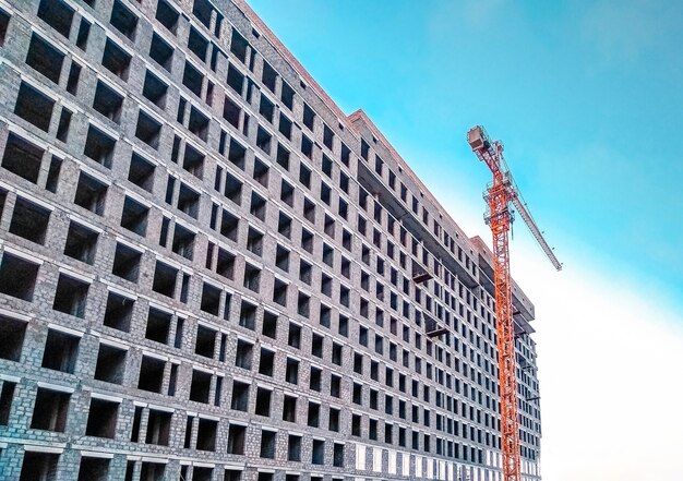 Grúa y construcción de viviendas contra el cielo azul