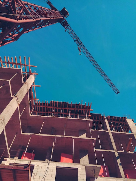 Grúa y edificio en construcción contra el cielo azul