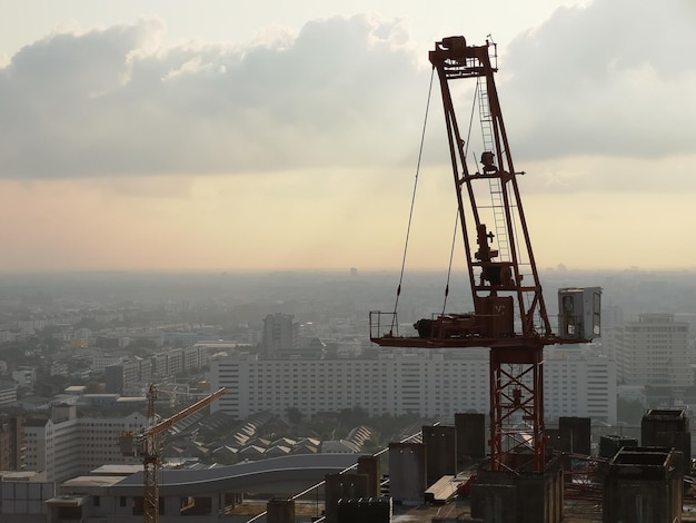 Grúa por los edificios contra el cielo durante la puesta de sol