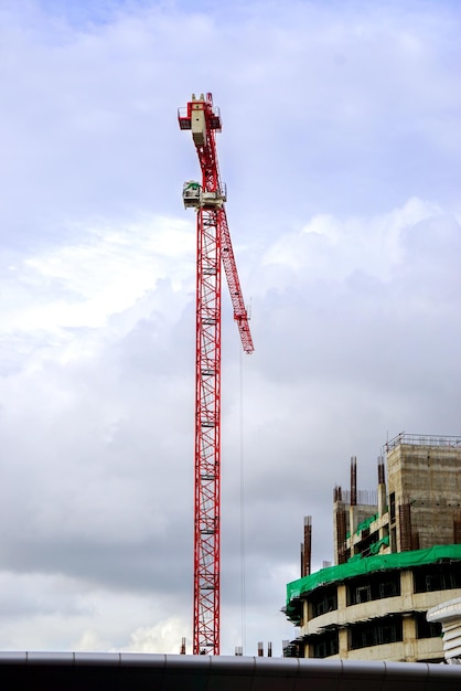 Grúa de elevación y grúa de construcción que trabajan en la construcción de edificios en un cielo azul brillante