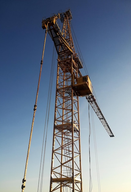 Grúa torre amarilla sobre un fondo de cielo azul.