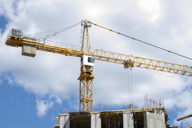 Una grúa torre de construcción en funcionamiento contra un cielo nublado en un día soleado El concepto de urbano