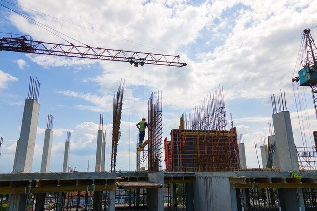 Grúa torre en edificio residencial de hormigón alto en construcción. Concepto de desarrollo inmobiliario.